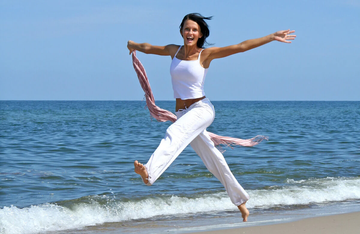 Donna atletica e sorridente che corre in spiaggia
